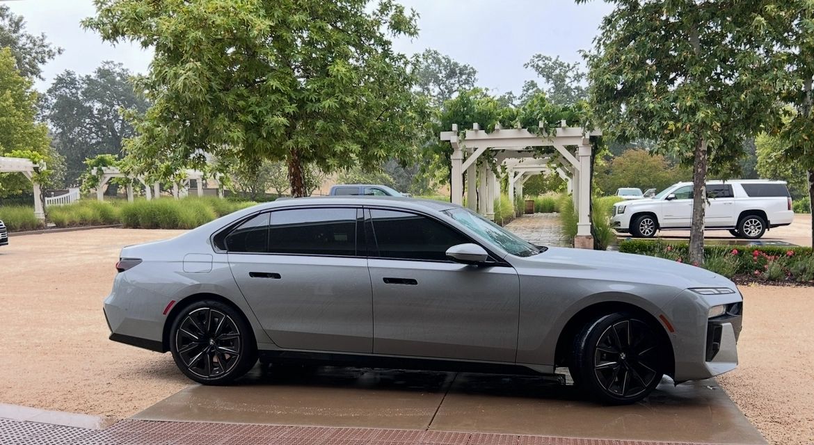 Silver BMW sedan parked under a covered entrance at a Monterey County winery, an example of the guest's own vehicle a Destination Drivers driver takes on a wine tour