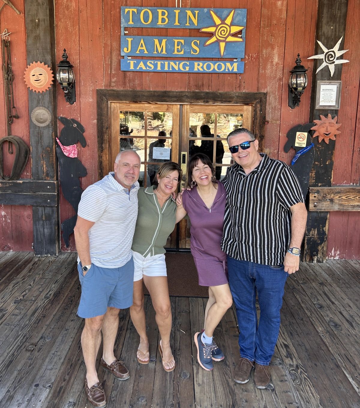Four smiling wine tour guests posing together outside the Tobin James tasting room in Paso Robles