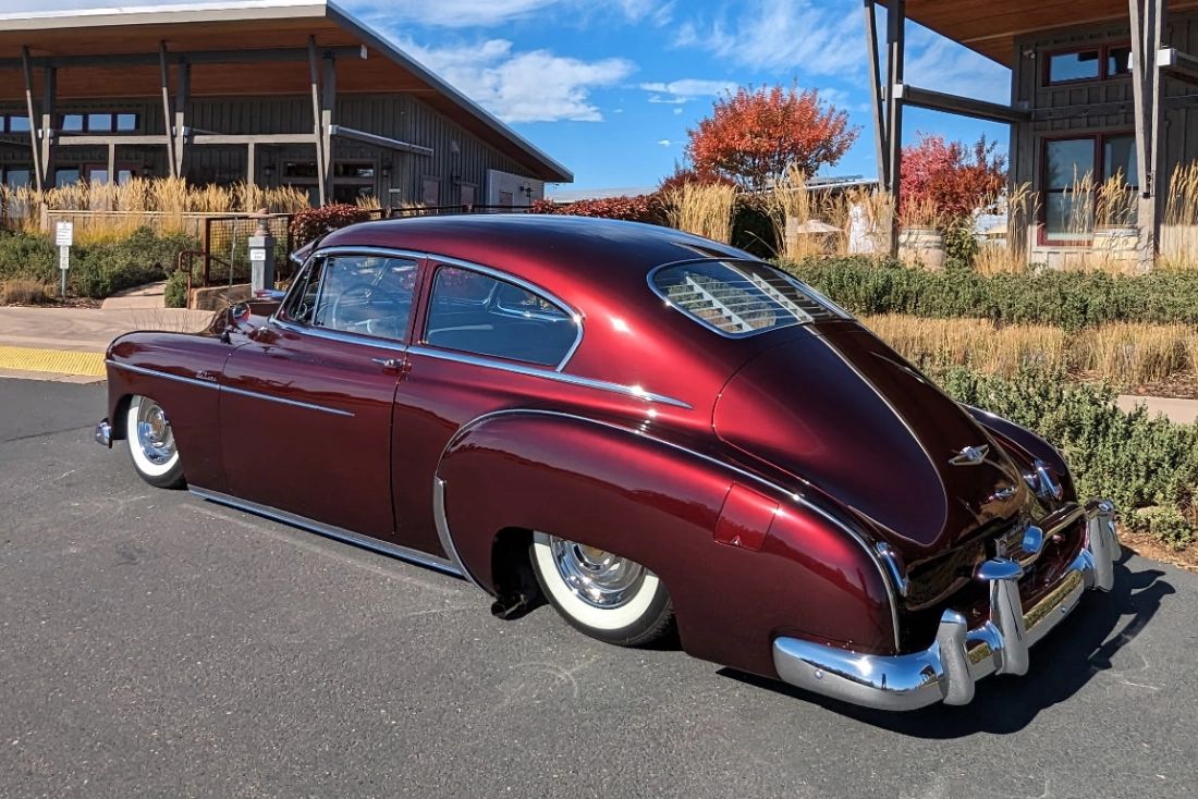 Classic maroon custom car with whitewall tires parked in front of a modern winery tasting room with fall colors in Plymouth, Amador County